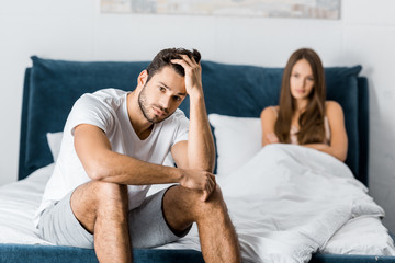 selective focus of sad man with sexual problems sitting in bed