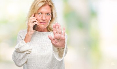 Poster - Middle age blonde woman talking on smartphone over isolated background with open hand doing stop sign with serious and confident expression, defense gesture