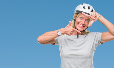 Sticker - Middle age caucasian cyclist woman wearing safety helmet over isolated background smiling making frame with hands and fingers with happy face. Creativity and photography concept.