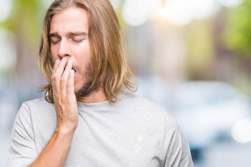 Sticker - Young handsome man with long hair over isolated background bored yawning tired covering mouth with hand. Restless and sleepiness.