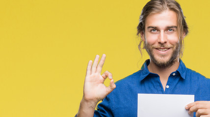 Sticker - Young handsome man with long hair over isolated background holding blank paper doing ok sign with fingers, excellent symbol