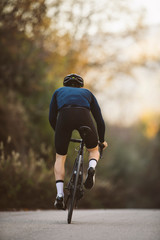 Wall Mural - A side shot of a professional slim cyclist riding up a mountain