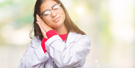 Sticker - Young arab doctor woman over isolated background sleeping tired dreaming and posing with hands together while smiling with closed eyes.