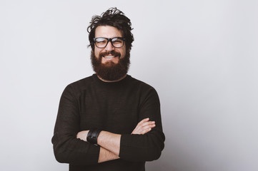 Wall Mural - Happy smart handsome young man wearing glasses and smiling at camera crossing arms on white background.