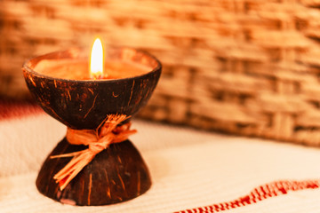 Burning spa aroma candle in coconut shell, cozy home interior 