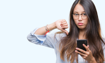 Poster - Young asian woman texting using smartphone over isolated background with angry face, negative sign showing dislike with thumbs down, rejection concept