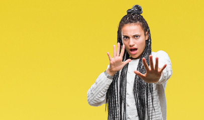 Sticker - Young braided hair african american girl wearing sweater over isolated background afraid and terrified with fear expression stop gesture with hands, shouting in shock. Panic concept.