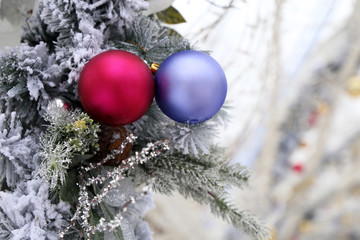 Wall Mural - Christmas balls and fir branches with New Year decorations covered with snow. Festive ornaments on winter street