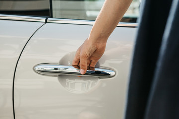 Close-up on a female hand opening the door of a new modern car.