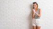 © Krakenimages.com - Young beautiful blonde woman over white brick wall disgusted expression, displeased and fearful doing disgust face because aversion reaction. With hands raised. Annoying concept.
