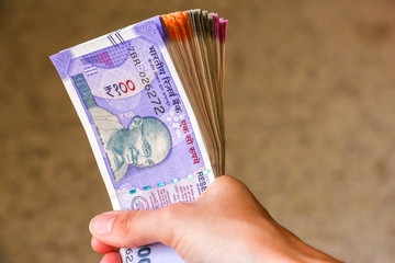 Woman's hands holding brand new indian 100, 200, 500, 2000 rupees banknotes.