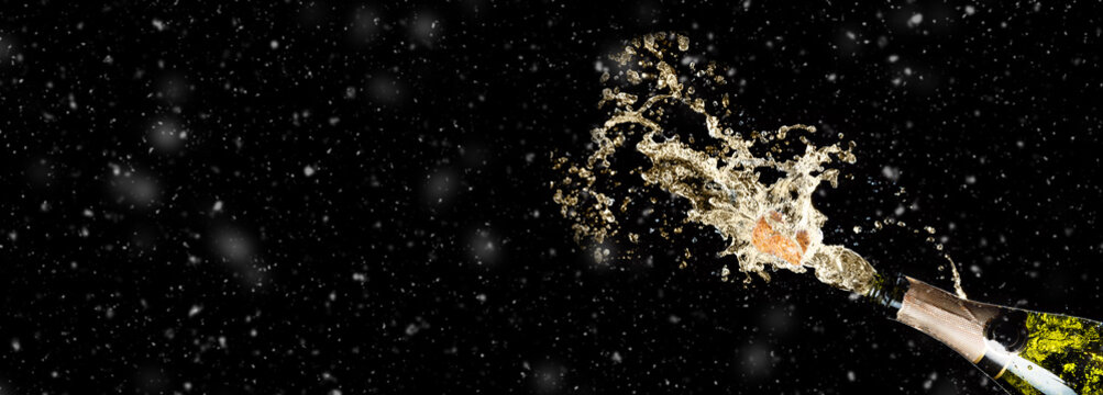 Wall Mural -  - Celebration theme with splashing champagne on black background with snow and free space. Christmas or New Year, Valentines day background.