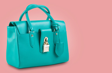 fashionable turquoise women bag with gold fittings on a pink pastel background
