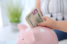 Little Girl Putting Money Into Piggy Bank, Closeup