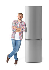 Wall Mural - Young man near closed refrigerator on white background