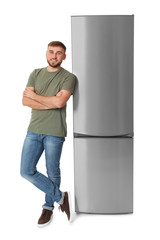 Wall Mural - Young man near closed refrigerator on white background