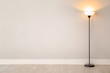Modern floor lamp against light wall indoors. Space for text