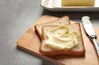 Tasty bread with butter and knife on wooden board