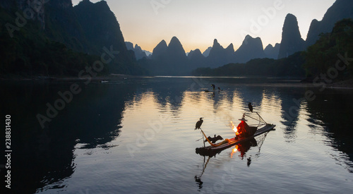 Cuadros en Lienzo Cormorant fisherman on raft in lake in Guilin, China, with three cormorant birds