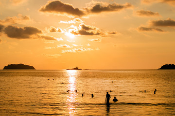 Wall Mural - Peoples to swim in the sea on sunset background. concept about people and fun, freedom, vacation