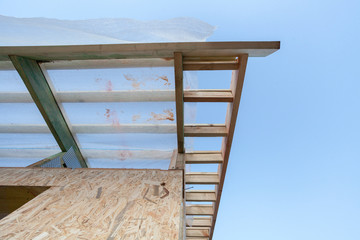 Wall Mural - Low angle top view eaves of new wooden roof with reliable supports and windproof membrane against blue sky