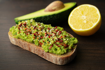 Appetizer avocado toast made from sourdough bread and chili pepper with black sesame seeds, as well as lemon juice