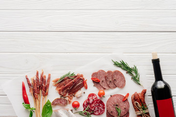 Wall Mural - flat lay with meat snacks and bottle of red wine on white wooden background