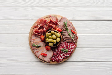 Wall Mural - top view of arrangement of various meat snacks and olives on white wooden backdrop