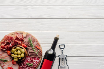 Wall Mural - flat lay with bottle of red wine, bottle opener and meat snacks on wooden surface