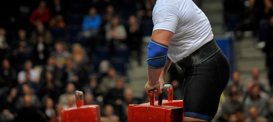  muscular sportsman doing farmer's walk exercise during his competition workout. Strongman sport