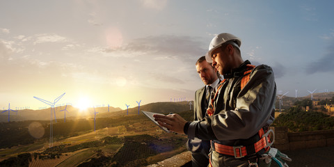 Wall Mural - windmill engineer and businessman planing new ecology project. they standing and looking in tablet. 