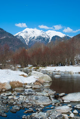 Sarca river with snow-covered banks and snowy mountains