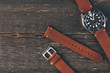 Brown leather handmade watch strap on mens luxury watch laying on dark rustic wooden table. Close Up. Copy space.