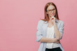 Waist up shot of contemplative young woman dressed in loose shirt, keeps hands partly crossed, wears optical glasses for good vision, stands against pink background with free space for your advert