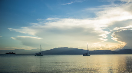 Wall Mural - North sea bay panoramic landscape with two sail boats in calm water surface and mountain horizon background silhouettes in morning sun rise quiet time  