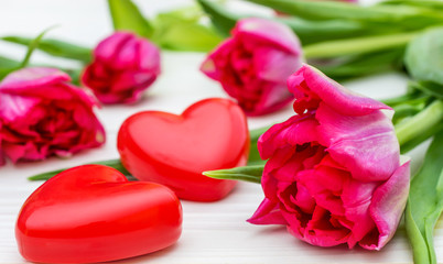 Wall Mural - Tulips with two red hearts on white wooden background.