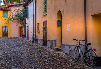  Bicycles next to a yellow walled house in a lovely small street along the city walls of medieval Cesena in Italy