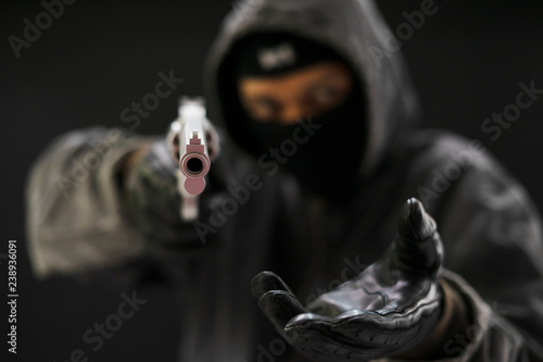 Fotografía Robber with a gun robbing intimidate.Crime and robbery concept.