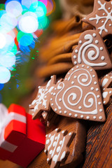 Sticker - Red gift box and decorated gingerbread Christmas cookies on lighting colorful background and wooden table