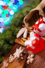 Sticker - Red and white gift box and decorated gingerbread Christmas cookies on lighting colorful background and wooden table