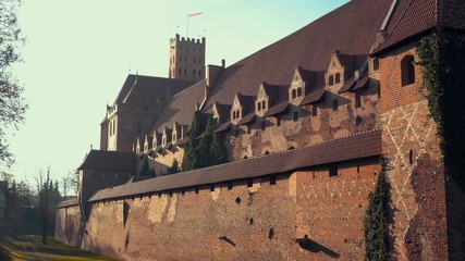 Wall Mural - Polish national flag flying over medieval Teutonic knights castle in Malbork