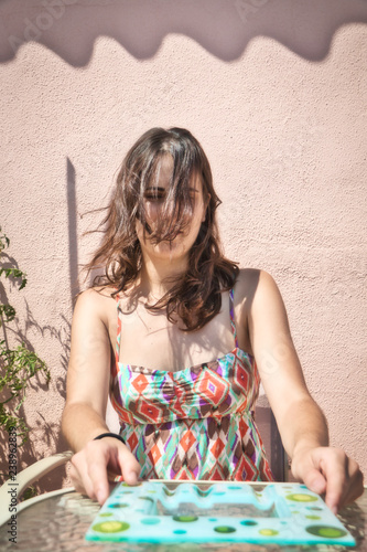 Fotografie, Obraz Pretty brunette girl with long hair very disheveled on the face, sitting behind
