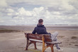 Young man relaxing on an old bench at the beach.