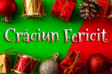 Merry Christmas In Romanian Language Concept Theme With Frame Made Of Baubles Covered In Glitter, Shiny Drums, Pine Cone And Gift Boxes On Red And Green Background With The Text Craciun Fericit