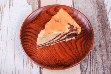 Slice of homemade marble cake on a wooden plate with vintage wooden table background