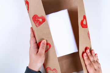 Diy. Gift wrapping for Valentine's Day. Kraft paper gift and potato stamp in the shape of a heart and red paint do it yourself on February 14th. Top view on a white background. step by step.