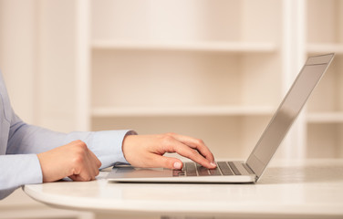 Business woman below chest working on her laptop in a cozy environment
