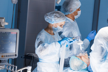 surgery preparations. surgical team preparing their patient for surgery adjusting oxygen mask on fac