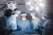 © alfa27 - Shot of a multiracial surgeon team consists of trained surgeons, trauma specialists and plastic surgeons, consulting during difficult operation proceed, standing before unconscious patient in O.R.