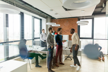 Canvas Print - Successful mixed race hipster male team in coworking space. Freelancers cooperate working in open space modern office